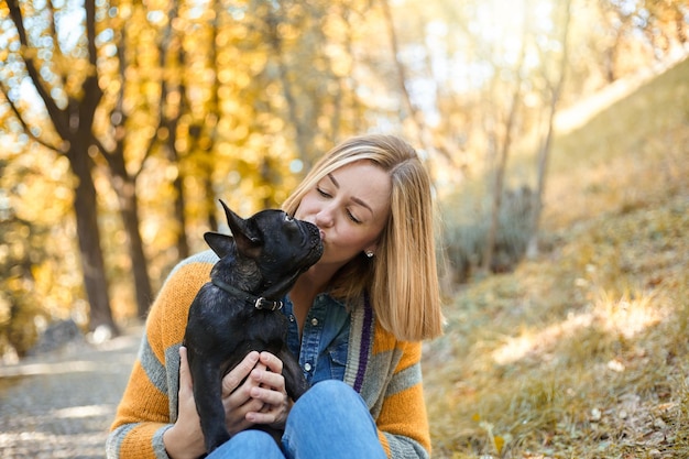 Primo piano sulla giovane donna felice con il cane all'aperto in autunno