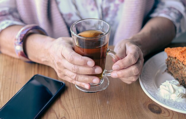 Primo piano sulla mano della donna nella caffetteria, gustando una tazza di tè e una torta di carote