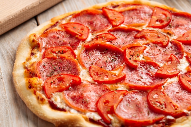 Primo piano sulla pizza al prosciutto con pomodoro con erbe secche sul tavolo di legno