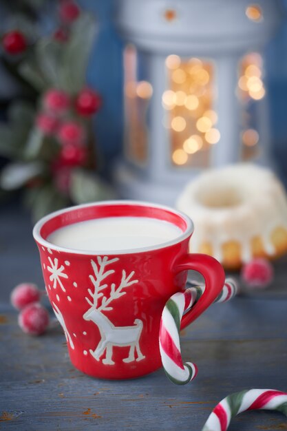 Primo piano sulla tazza rossa con latte e decorazioni natalizie