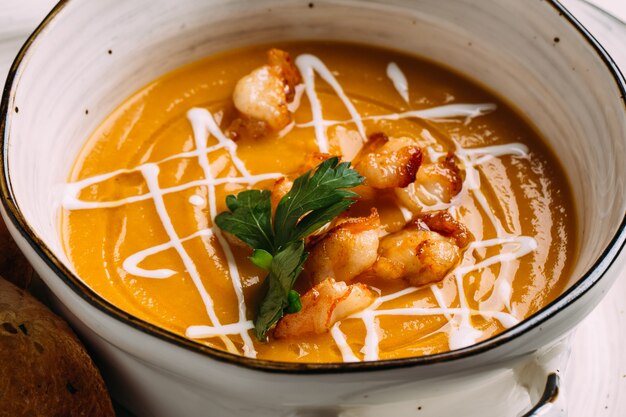 Primo piano sulla zuppa di crema di zucca con gamberi fritti in pastella