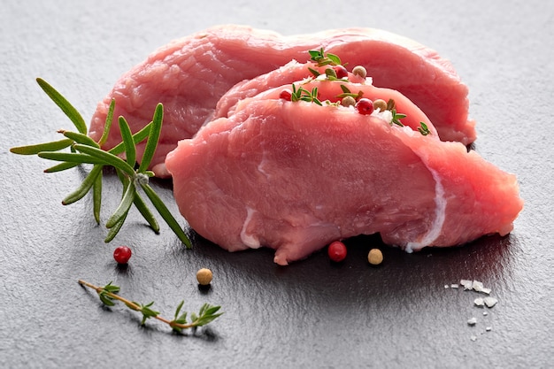 Primo piano sulle fette di carne cruda del manzo. Filetto con erbe e spezie sul bordo di pietra.