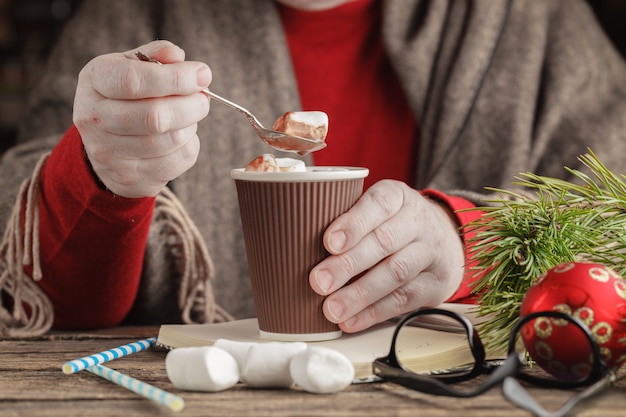 Primo piano sulle mani che eliminano caramella gommosa e molle dalla tazza di cioccolata calda