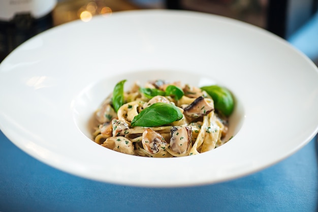 Primo piano sulle tagliatelle gourmet con funghi selvatici in un piatto bianco