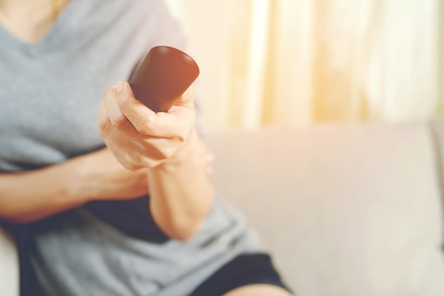 Primo piano Telecomando della televisione in un uomo casual tenere la mano che punta al televisore e accenderlo o spegnerlo selezionare il canale guardando la partita di calcio in tv è a casa nel soggiorno rilassarsi