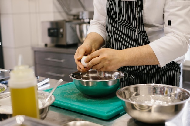 Primo piano Un cuoco maschio sta pulendo le uova sode nella cucina di un ristorante