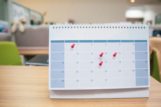 Primo piano un perno rosso sul calendario da tavolo vuoto.