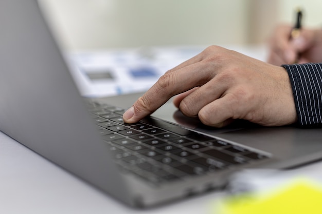 Primo piano Un uomo d'affari che lavora in una stanza privata, sta scrivendo sulla tastiera di un laptop, usa un messaggero per chattare con un partner. Concetto di utilizzo della tecnologia nella comunicazione.