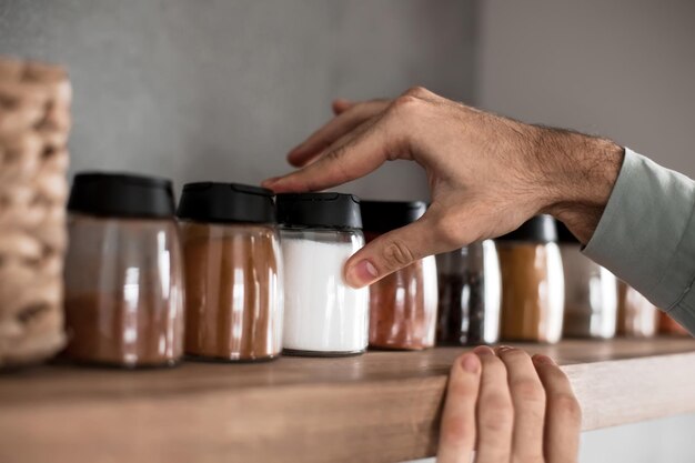 Primo piano un uomo prende le spezie dallo scaffale della cucina