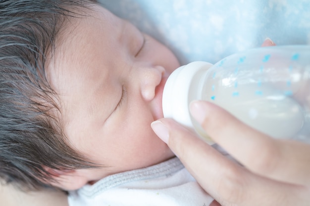 Primo piano una bambina sta succhiando il latte materno dalla bottiglia