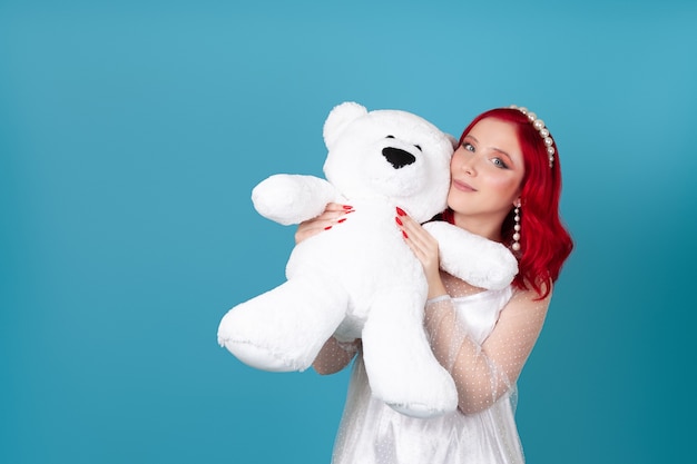 Primo piano una donna contenta felice in un vestito bianco preme un grande orsacchiotto bianco al suo fronte