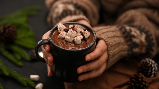 Primo piano Una donna passa in mano una tazza di cioccolata calda con marshmallow Bevande speciali invernali