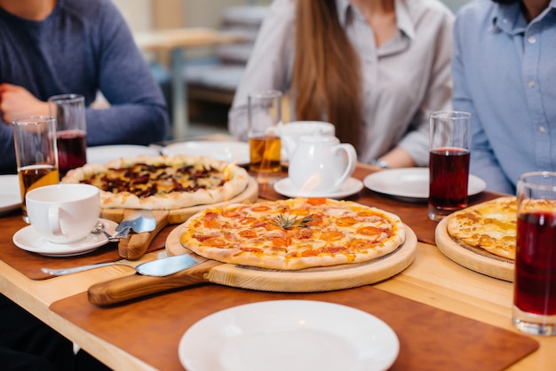 Primo piano unico della pizza calda sul fuoco durante una cena amichevole.