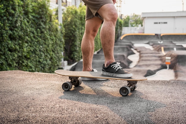 Primo piano uomo asiatico che tiene surfskate o skateboard in pumptrack skate Park