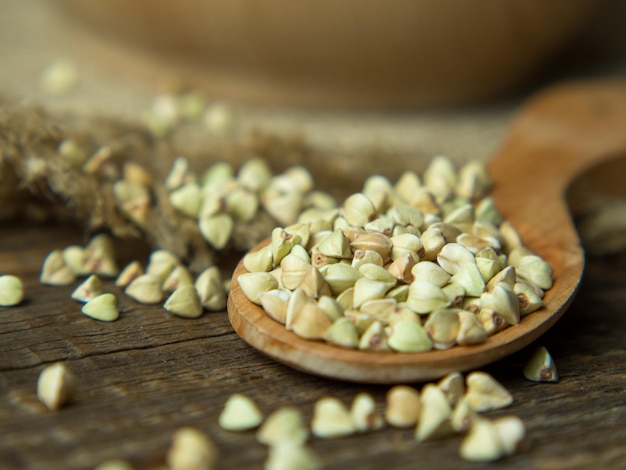 Primo piano verde del grano saraceno in una ciotola di legno su una vecchia tavola di legno. cibo salutare