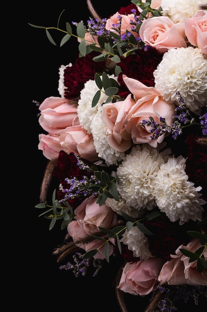 Primo piano verticale di un lussuoso bouquet di rose rosa e fiori bianchi su sfondo nero