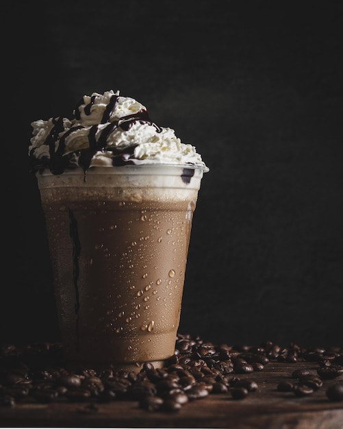 Primo piano verticale di una tazza di plastica di caffè freddo con una crema alla vaniglia