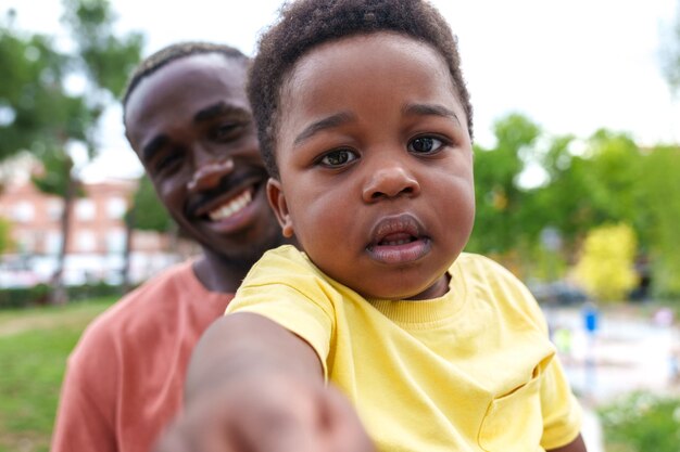 Primo piano vibrante Padre africano e bambino che esplorano il parco cittadino Ritratto colorato di connessione