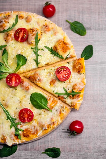 Primo piano vista dall'alto della pizza vegetariana con pomodori ed erbe aromatiche su sfondo tavolo in legno