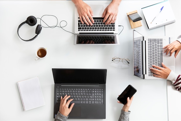 Primo piano vista dall'alto delle persone che lavorano con il computer portatile su una scrivania bianca Concetto di ufficio che lavora insieme