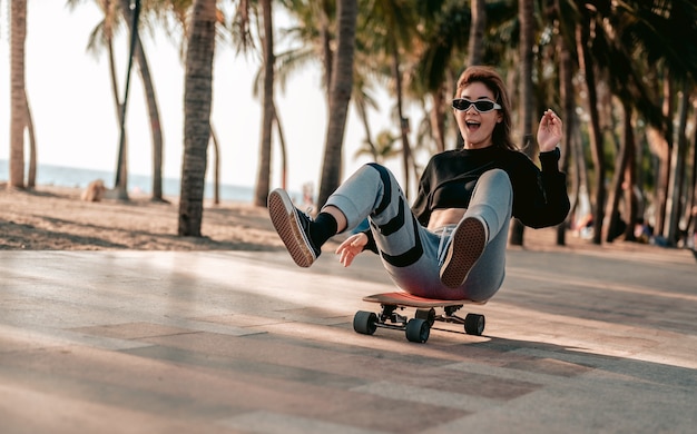 Primo pianoLe donne asiatiche fanno surf o pattini a bordo all'aperto in una bella giornata estiva