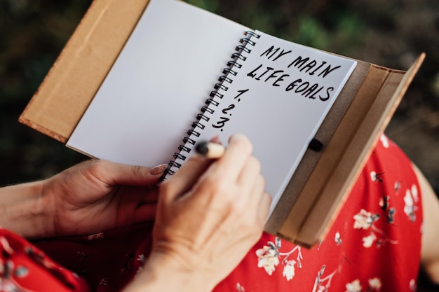 Principali obiettivi della vita come impostare e raggiungere gli obiettivi della vita Le mani femminili scrivono su un taccuino l'iscrizione