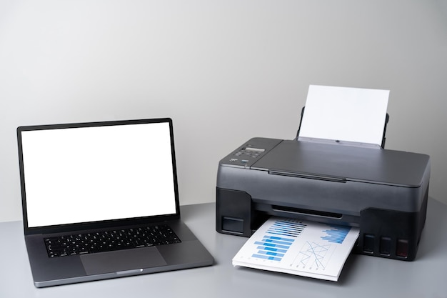 Printer and laptop on grey table in office