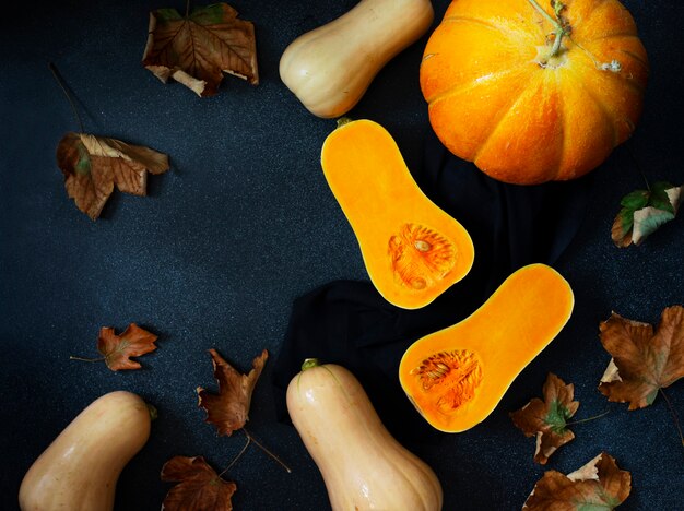 Priorità bassa della zucca di autunno, varie zucche e foglie gialle. Ringraziamento e concetto di Halloween. Composizione piatta in natura morta. Sfondo nero, vista dall'alto. Spazio per il testo.