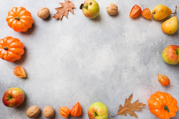 Priorità bassa di autunno con le foglie gialle, le pere delle mele delle zucche e le noci