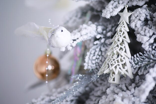 Priorità bassa di festa di Natale. Pallina d'argento e di colore appesa a un albero decorato con bokeh e neve, spazio copia.