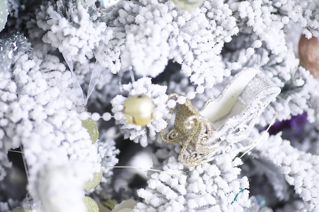 Priorità bassa di festa di Natale. Pallina d'argento e di colore appesa a un albero decorato con bokeh e neve, spazio copia.