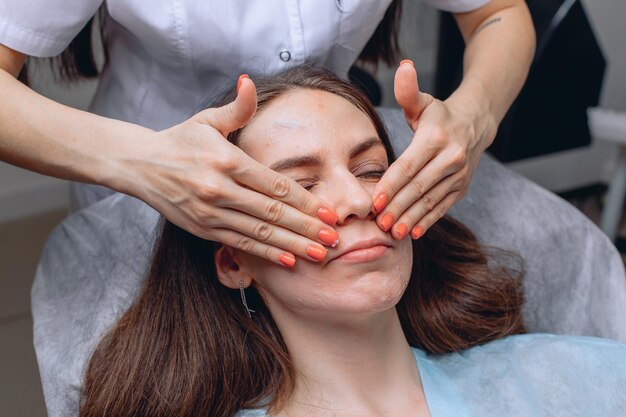 Procedura cosmetica in uno studio di bellezza per la cura della pelle. Il cosmetologo applica una crema con le sostanze necessarie sul viso della ragazza.