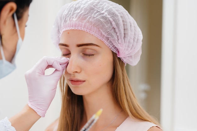Procedura cosmetica per riempire il solco nasolacrimale e mesoterapia intorno agli occhi per una giovane bella ragazza. Cosmetologia moderna.