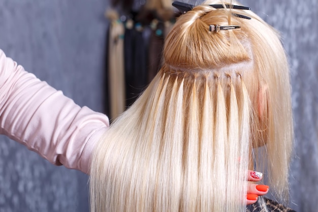 Procedura di estensione dei capelli il parrucchiere fa le estensioni dei capelli alla ragazza bionda in un salone di bellezza se