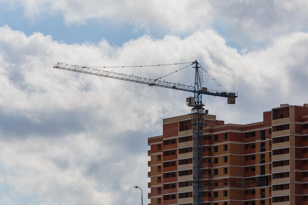 Processo di costruzione di un grande condominio residenziale con gru su sfondo con cielo nuvoloso