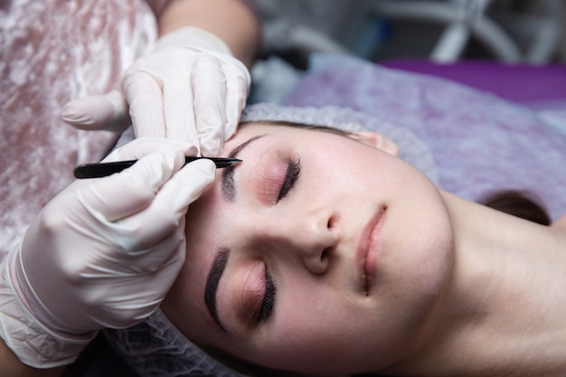 Processo di creazione delle sopracciglia. Bella donna con gli occhi chiusi sulla procedura.