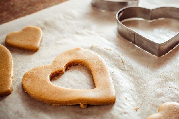 Processo di creazione di biscotti allo zenzero sotto forma di cuori su un tavolo di legno