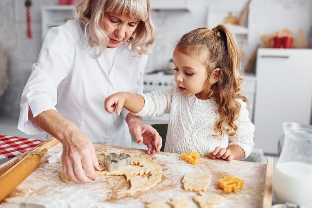 Processo di insegnamento La nonna anziana con la sua nipotina cucina dolci per Natale in cucina