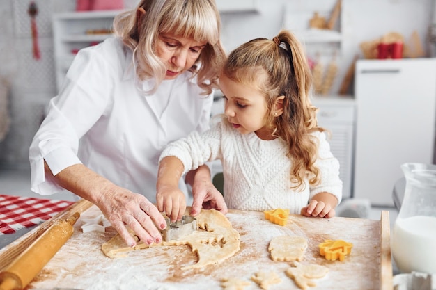 Processo di insegnamento La nonna anziana con la sua nipotina cucina dolci per Natale in cucina