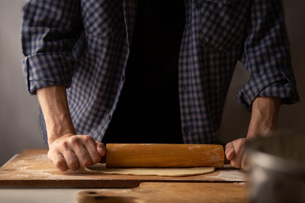 Processo di laminazione della pasta Un uomo con una camicia a quadri rotola la pasta per gli gnocchi con un mattarello