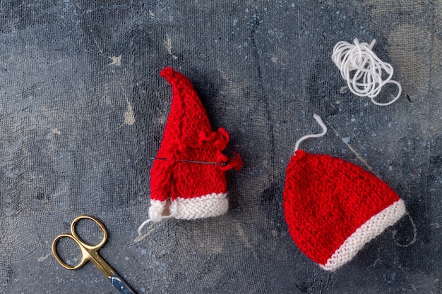 Processo di lavorazione a maglia di cappelli di Babbo Natale su uno sfondo blu passaggio 4