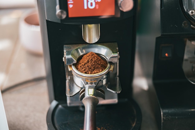 Processo di macinazione dei chicchi di caffè che vengono versati in un portafiltro utilizzando la macchina da caffè