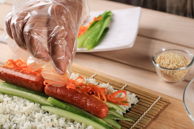 Processo di preparazione del rotolo coreano Gimbap (Kimbob o Kimbap) a base di riso bianco al vapore (Bap) e vari altri ingredienti e avvolto con alga marina. Metti la carota sul riso