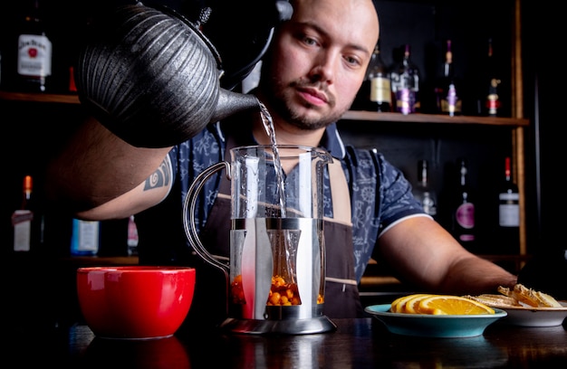 Processo di preparazione del tè, cerimonia del tè. Il barista versa acqua calda nel bollitore per preparare il tè alla frutta di mare