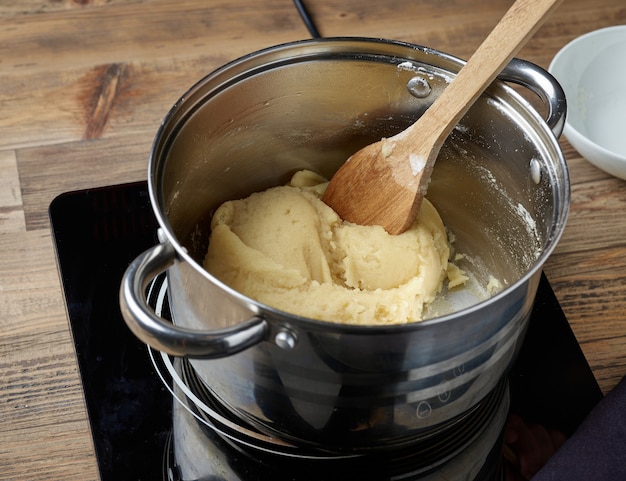 Processo di preparazione dell'impasto per bignè o bignè. pentola di pasta sul piano cottura a induzione elettrica