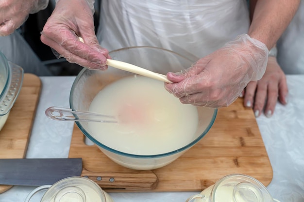 Processo di produzione del formaggio con un codino Mani che impastano il formaggio nel latte