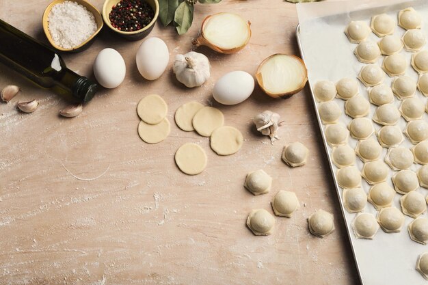 Processo di produzione di gnocchi con carne su tavola di legno. Pelmeni e ingredienti crudi fatti in casa.
