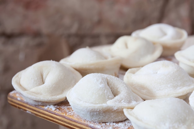 Processo di produzione di pelmeni fatti in casa (gnocchi) su tavola di legno.