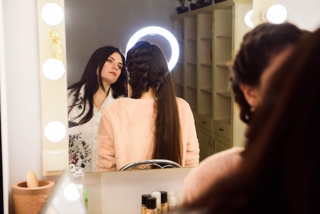 Processo di trucco. Truccatore che lavora con il pennello sulla faccia del modello. Ritratto di giovane donna nell'interno del salone di bellezza.