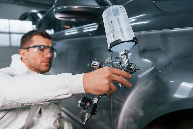 Processo di verniciatura dell'auto L'uomo in uniforme sta lavorando nel servizio auto